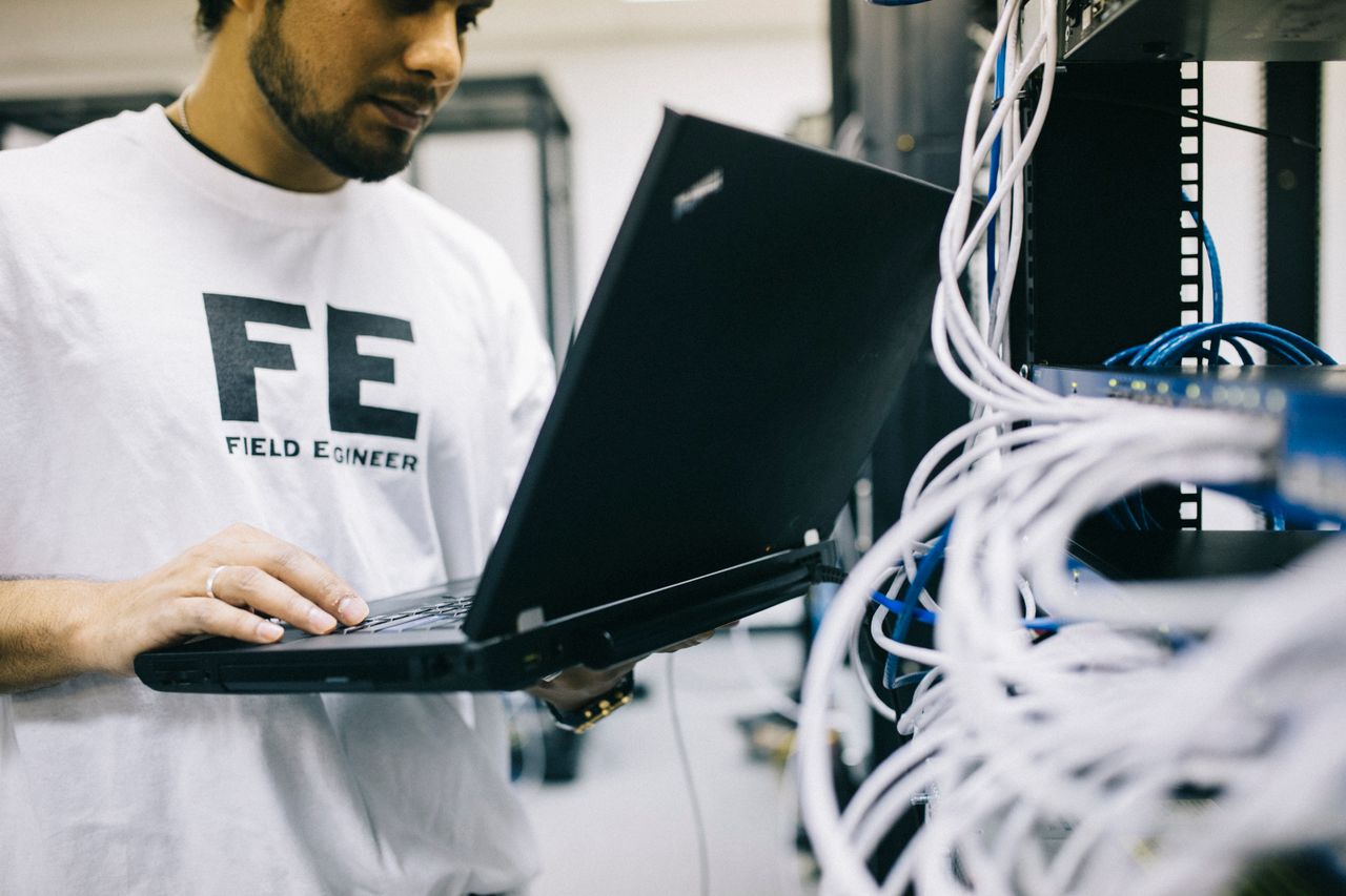 مهندس شبكات سعودي في مكتب بالرياض يراجع مخطط VLAN لشبكة الموظفين والضيوف والكاميرات