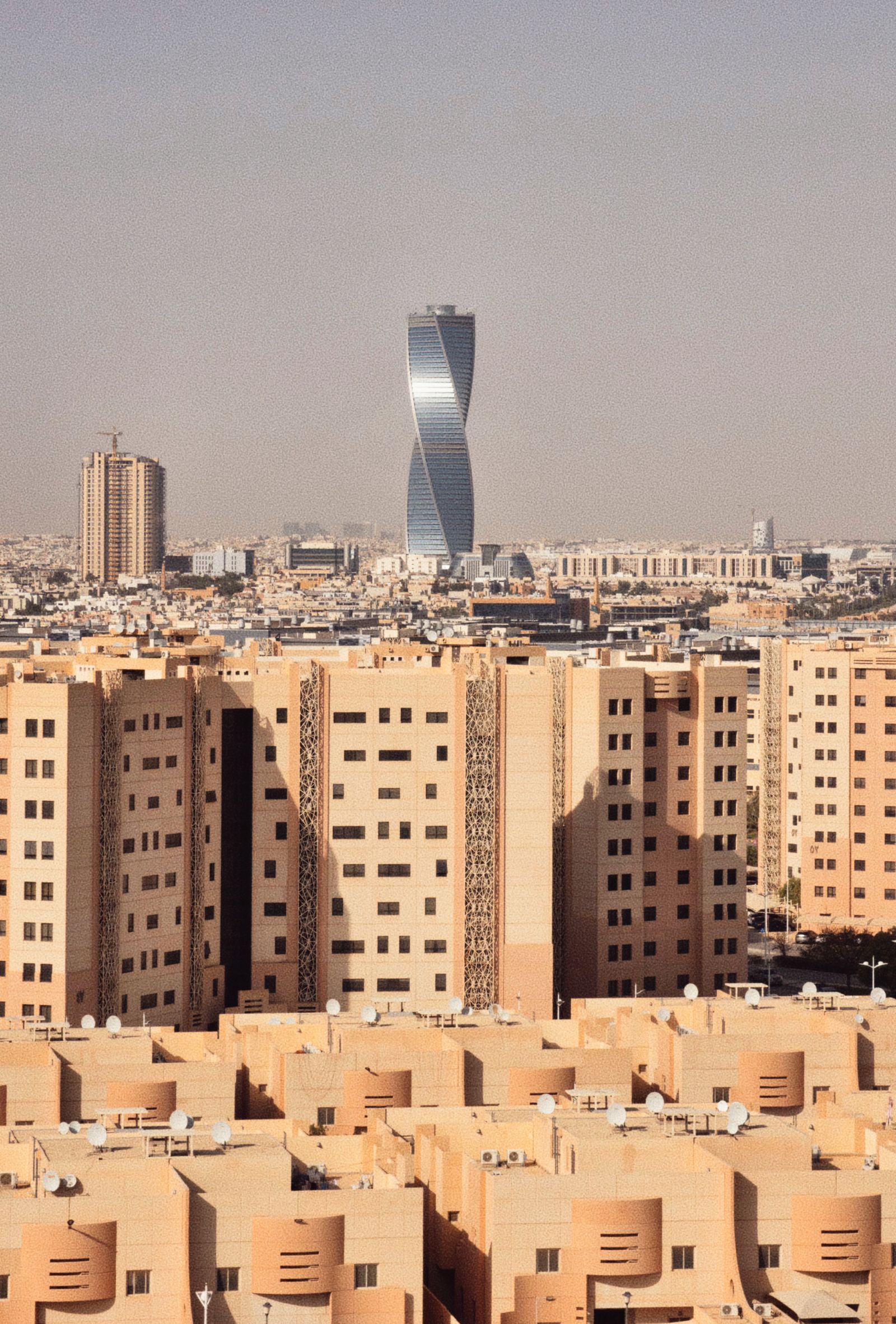 العلم السعودي ومشهد المدينة في الرياض ليلًا